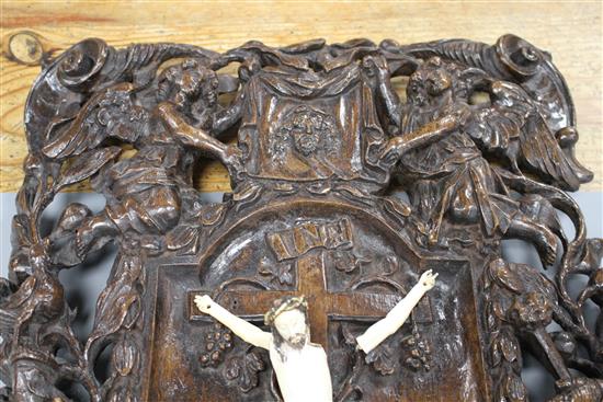 A 19th century European carved walnut and ivory crucifix, the ivory Corpus Christi on a pierced plaque decorated with angels, scrolls a